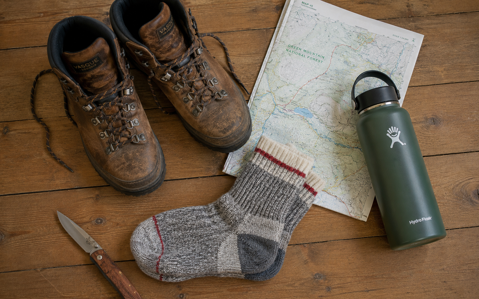 A backpack and gear laid out on a wooden floor